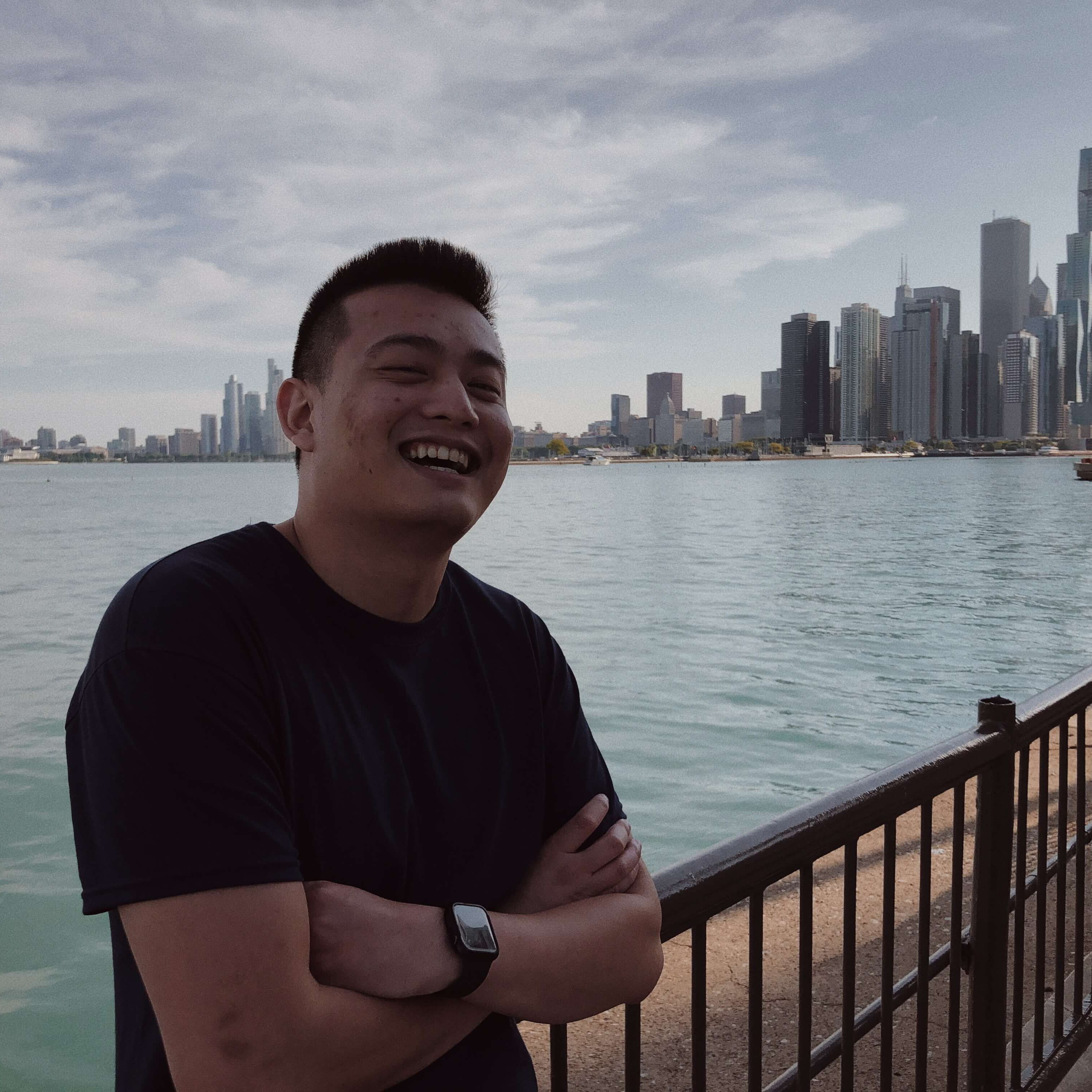 man smiling leaning up against railing